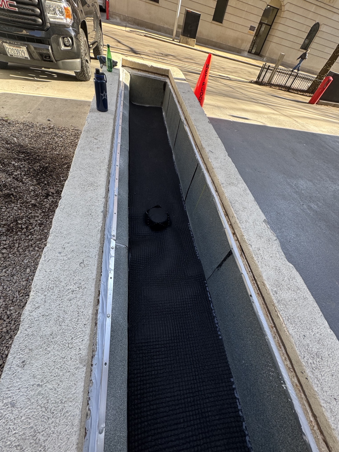 Concrete planter with its renewed black waterproofing membrane and drain
